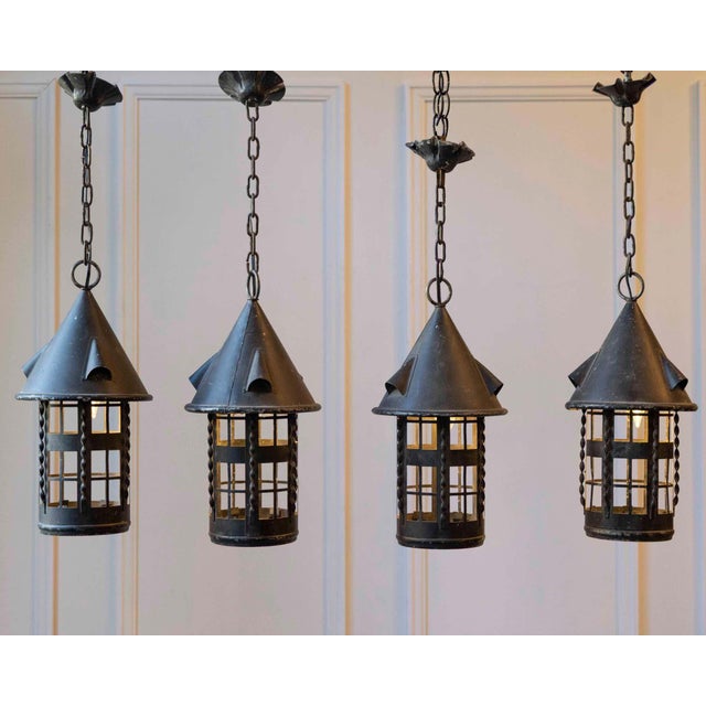 A charming set of four early 20th-century French iron lanterns, each crafted with a whimsical, turret-like silhouette that...
