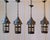 A charming set of four early 20th-century French iron lanterns, each crafted with a whimsical, turret-like silhouette that...