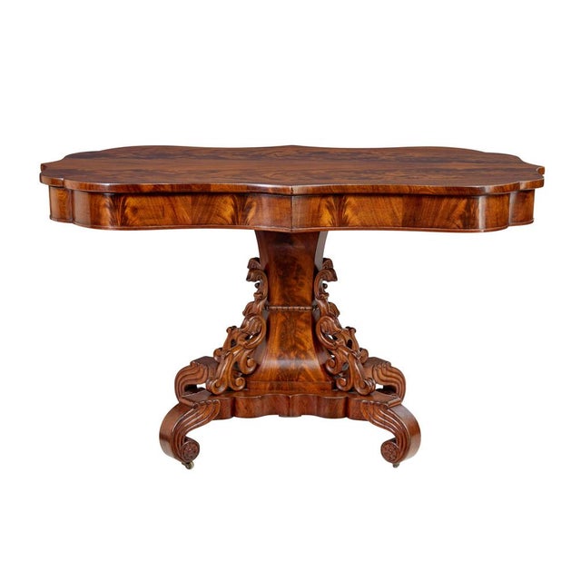 19th century danish carved flame mahogany center table circa 1860. Beautifully shaped top surface with striking half...