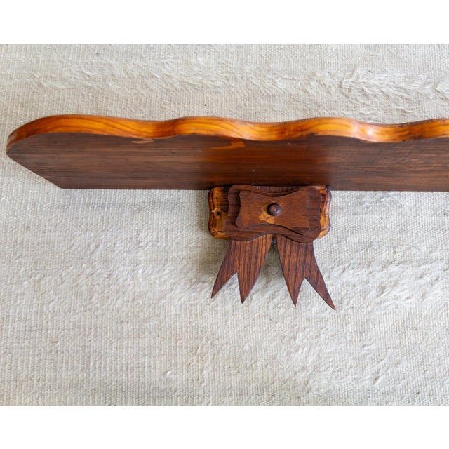 This handcrafted, one-of-a-kind wall-mounted wood shelf features a scalloped edge and two large bow brackets below the...