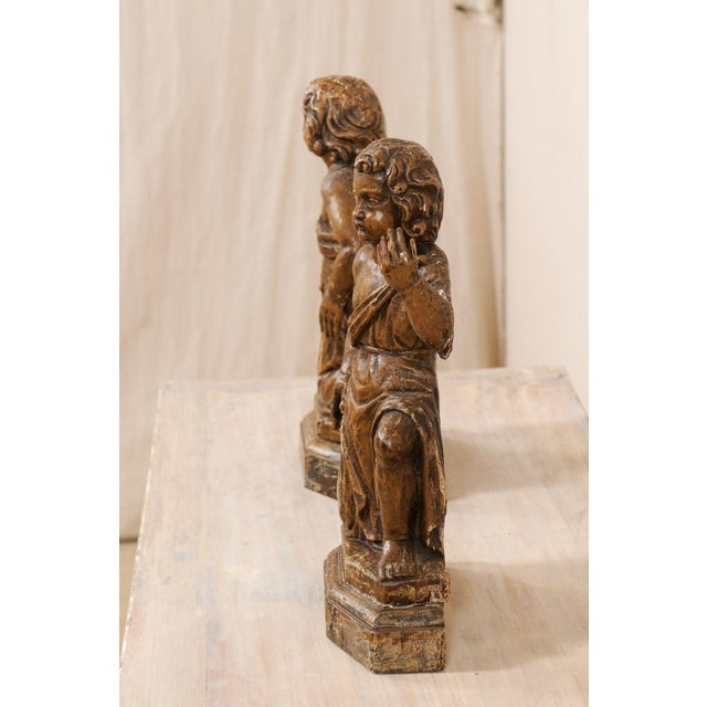 A French pair of carved-wood cherub figures from the 19th century. This antique pair of wooden figurines from France have...