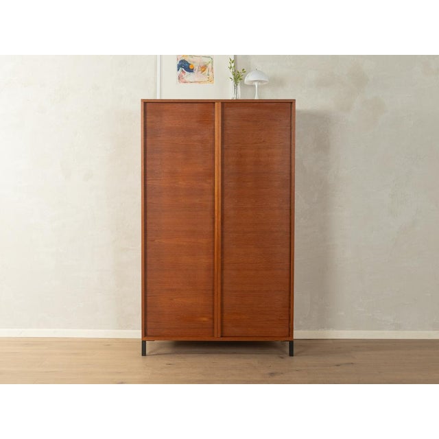 Classic wardrobe by Günter Renkel for REGO from the 1960s. Teak veneer frame with two doors, four shelves, and black...