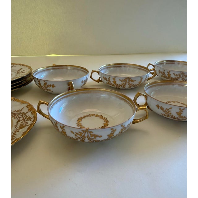 A distinguished set of six double-handled bouillon cups and five matching saucers in fine white Limoges porcelain, bearing...