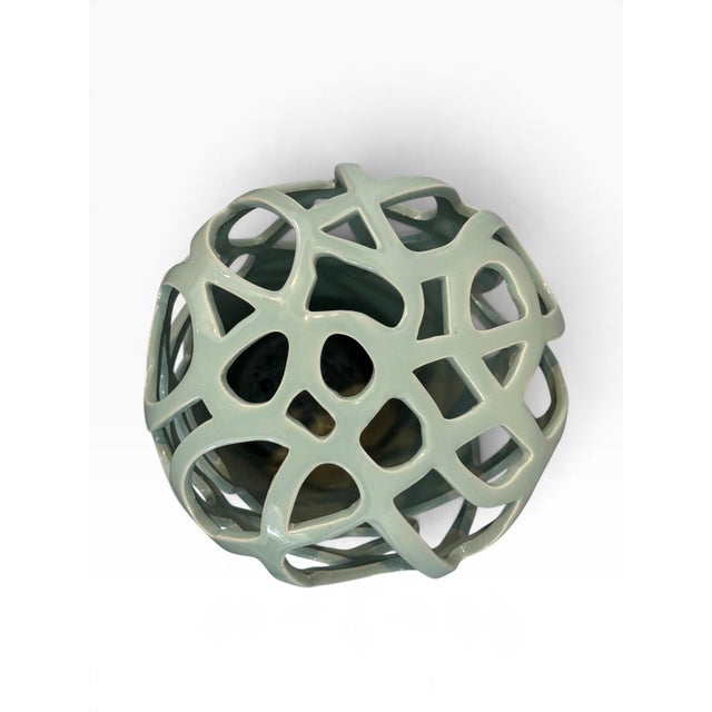 A dramatic contemporary vase in a soft celadon-sage glaze. The lower body is a solid tapered cylinder; the upper section...