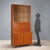 Larch veneered storage unit with brass accents, featuring a display case, drop-down door, and hinged doors. In good...