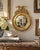 A Federal-style brass convex mirror crowned with a carved eagle, its wings outstretched above olive branches—an enduring...