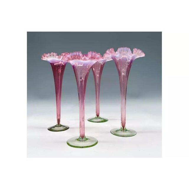 A matched set of four Victorian cranberry opal glass trumpet vases, circa 1890, hollow stemmed with crimped rims with a...