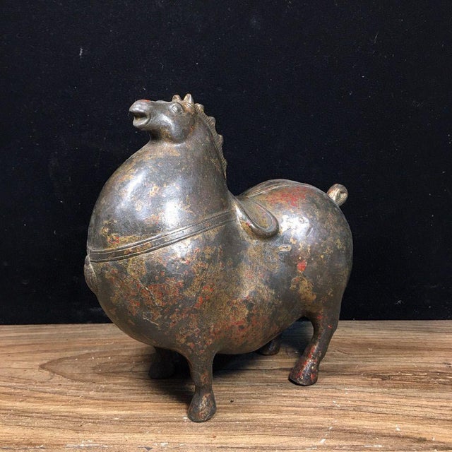 This charming antique bronze sculpture depicts a horse in a dynamic, stylized pose reminiscent of Tang dynasty ceramic...