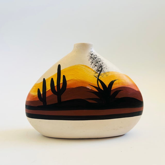 A vintage Southwestern pottery vase. Flat oval shape with hand painted scenery of the sides. Measures 6.5"W x 2.25"D x 5"H
