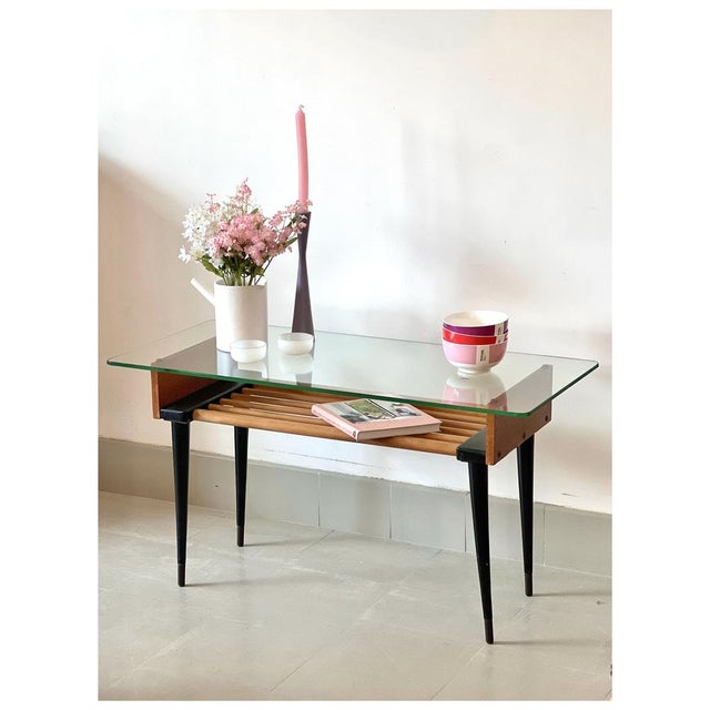 Elegant coffee or side table in wood and glass. The structure partly painted in black and the slender wooden rots make...