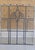 This likely antique leaded glass window panel features a symmetrical geometric design with a central stylized floral motif...