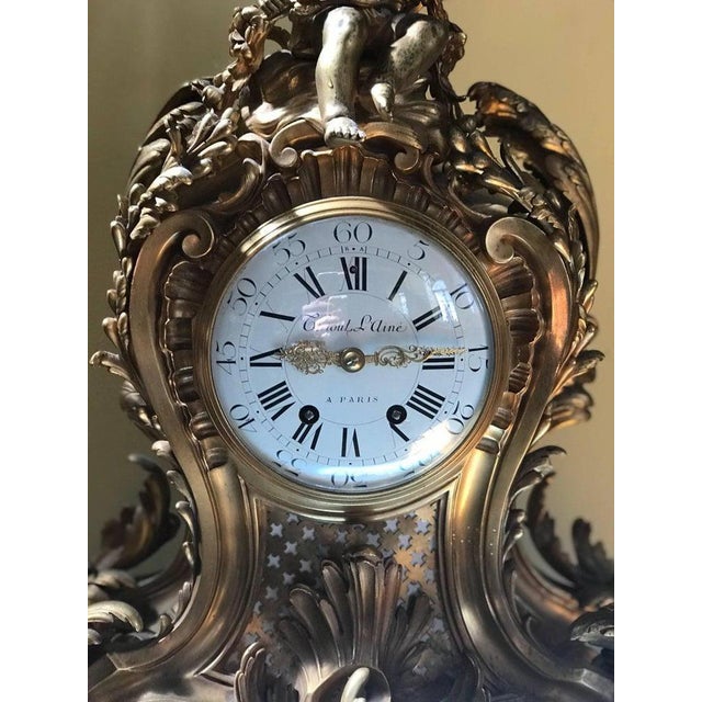 A 19th century impressive ormolu french mantle clock the ribbon arch over seated cherub with floral garland in the rococo...