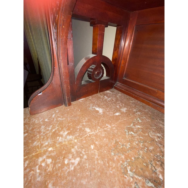 This sideboard has a marble top, mirrored hutch, and detailed woodwork. It is characteristic of late Victorian or...