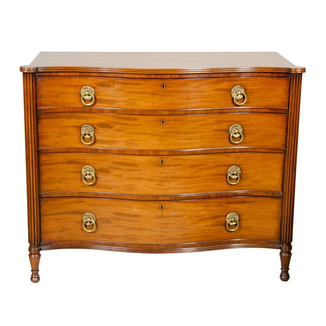 Serpentine top over four graduated drawers flanked by reeded columns. Brass ring handles on drawers , raised on circular...