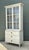This vintage painted wood and glass cabinet, dating to the mid-20th century, combines practical storage with understated...