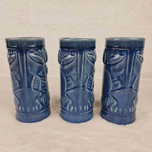 Three bluish gray ceramic Hawaiian tiki mugs. Made by Libbey. Both in excellent condition. Marked Libbey on the bottoms.