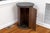 A mid-20th century, black circular marble top pedestal cabinet with a fluted column, hinged door storage compartment,...