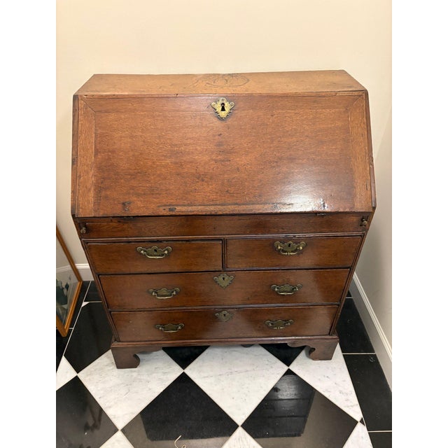 An antique English Georgian style oak secretary bureau (or slant-front desk) with deep amber-brown patina, a fall-front...