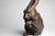 A finely cast Japanese bronze okimono depicting a seated rabbit, its head lowered and both forepaws raised to its face....