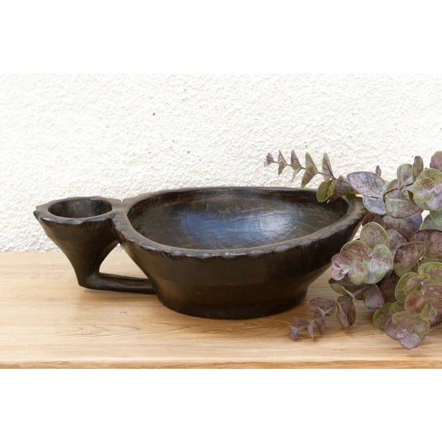 A story carved in a single piece of wood, a testament to shared traditions. This antique tribal vessel from the...