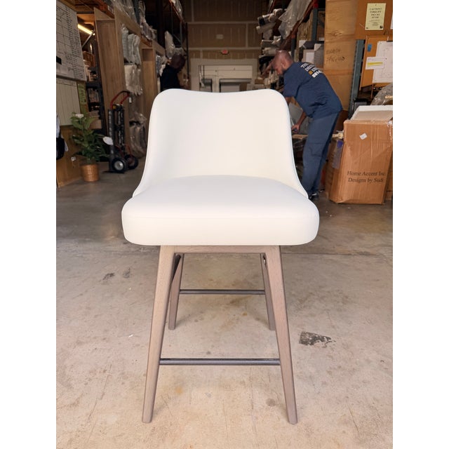 Contemporary swivel counter stool featuring a sleek, tailored silhouette upholstered in soft ivory leather for a clean and...
