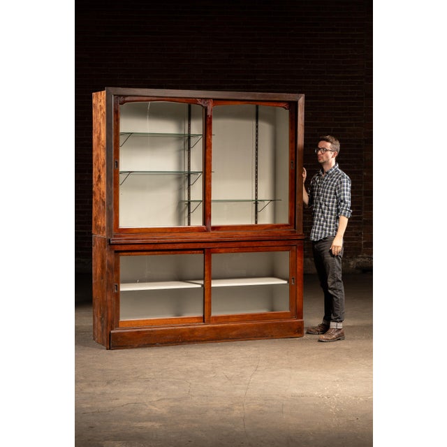 Two-piece oak display cabinet featuring sliding glass doors and adjustable interior shelving. The upper section houses...