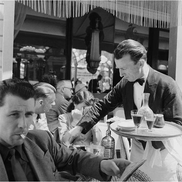 "Cafe Culture" by Bert Hardy A waiter serving clients on the terrace of a cafe on the Champs-Elysees, Paris, June 1951....
