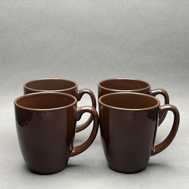 • This is a set of four vintage Corelle Stoneware coffee mugs featuring a rich, solid chocolate brown glaze. These durable...