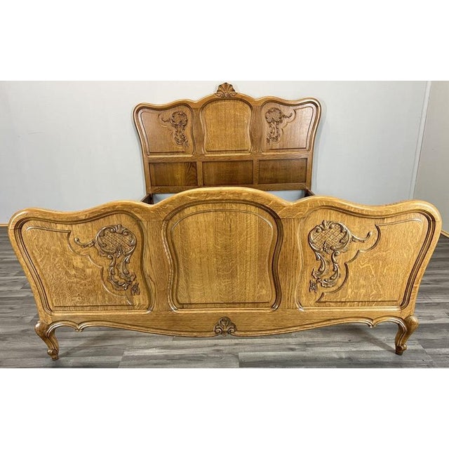 This Vintage French Louis bed frame features beautifully carved detailing, elegant curved silhouettes and a warm oak...