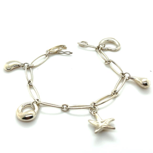A distinctive Tiffany & Co. Elsa Peretti bracelet crafted in sterling silver, featuring five decorative charms suspended...