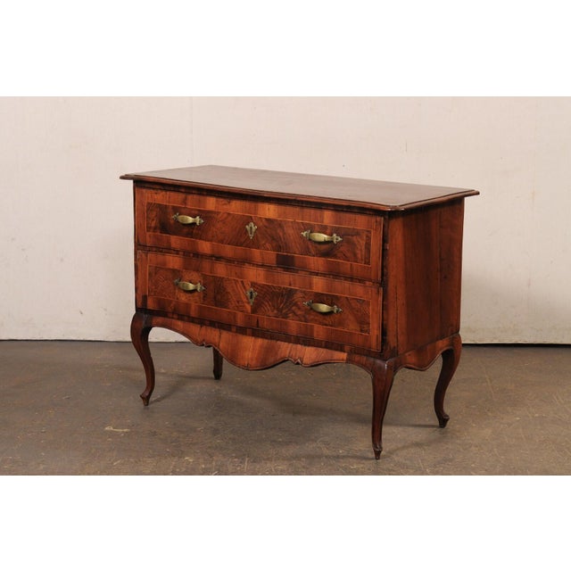 An Italian raised two-drawer chest, with decorative inlay and brass hardware, from the 18th century. This antique...