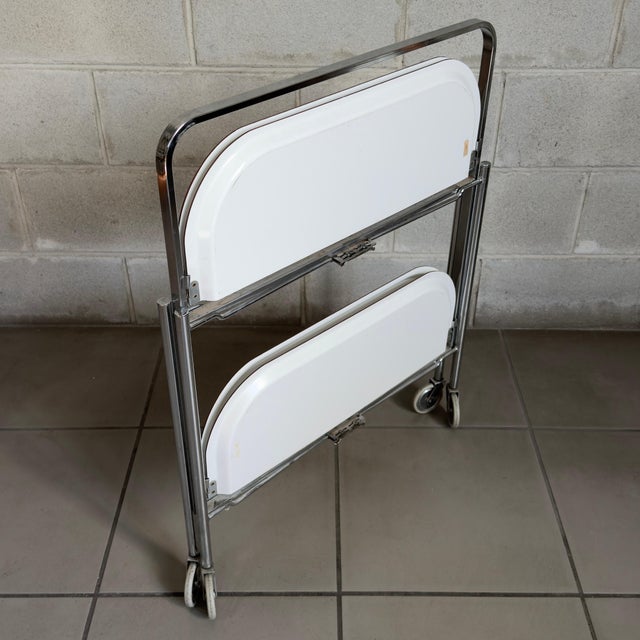 Practical and minimalist, this modernist folding bar cart features a polished chrome-plated metal frame and double,...