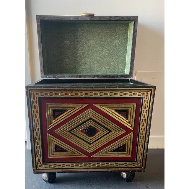 A cube form storage box with an elaborate embossed metal trim. The box is raised upon ornate metal feet. A dramatic and...