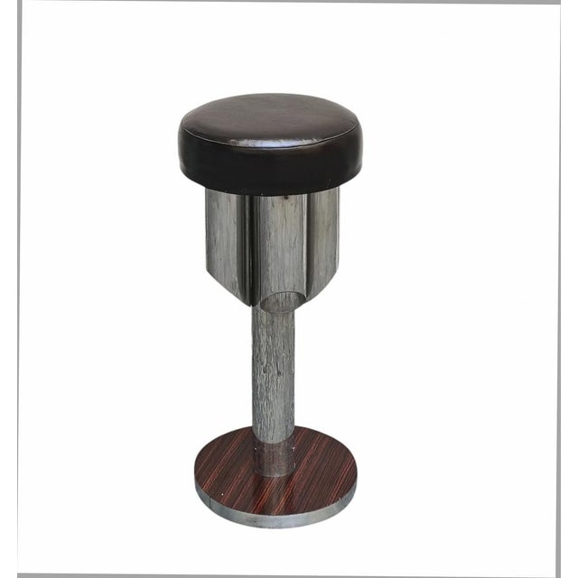 A tall bar stool made in Italy in the 1970s. Steel frame, padded seat upholstered in brown faux leather. It has an...