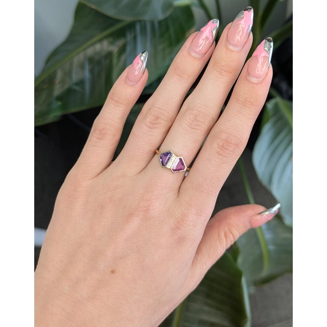 A captivating 1.9ct pink and purple sapphire takes center stage, showcasing a unique blend of romantic hues set in solid...