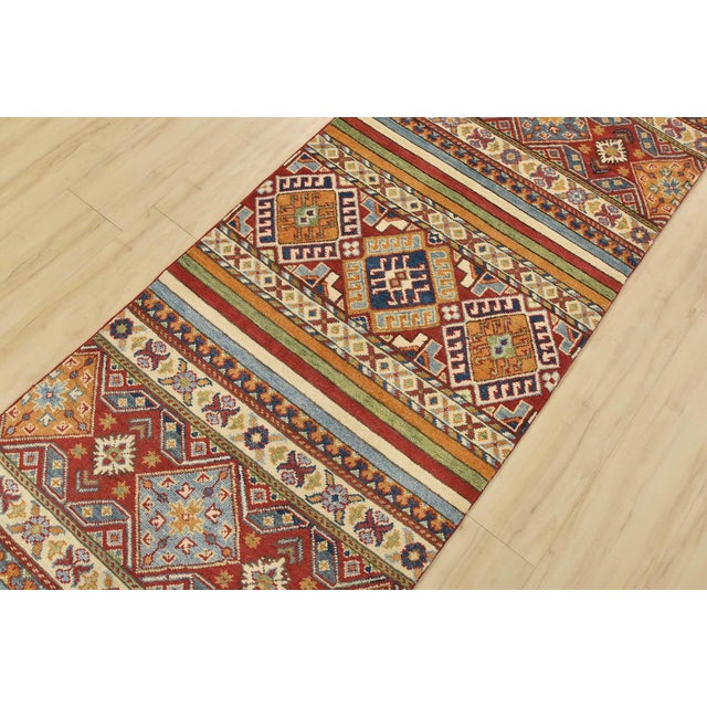 A tribal Khorjin runner hand-knotted with fine wool on a cotton foundation. This rug features multicolored stripes adorned...