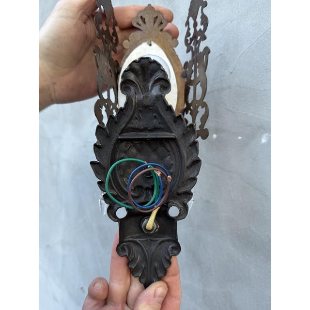 A charming pair of vintage Italian wall sconces sourced in Turin, featuring ornate cast-brass bodies adorned with hand-...