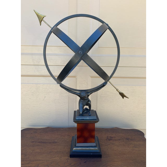 A Grand Tour–style classical armillary sphere being held up by the mythological figure Atlas, mounted on a square burl...