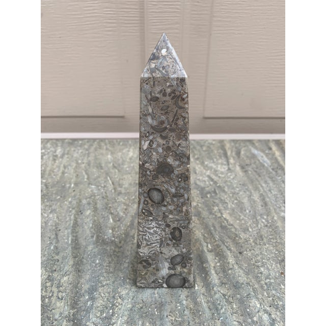 A beautifully proportioned marble obelisk in richly veined shades of brown, cream, and grey. The sculptural silhouette and...