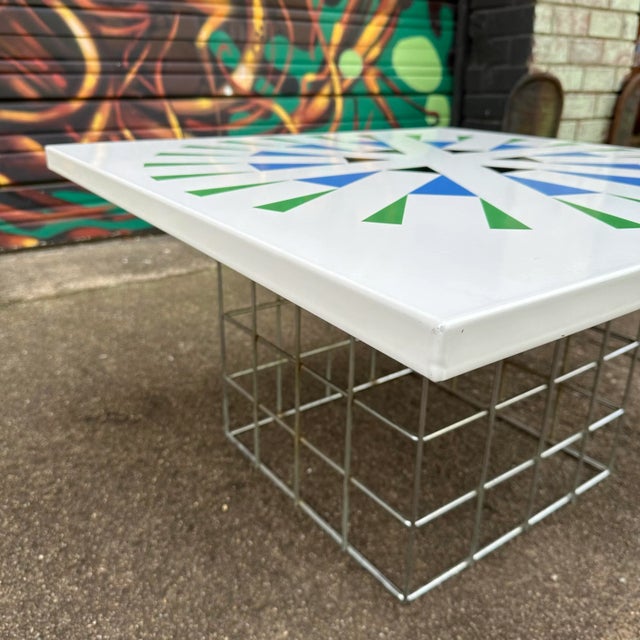 This square-shaped side table top is made of enamel and features a blue, green, and black geometric pattern on its top...