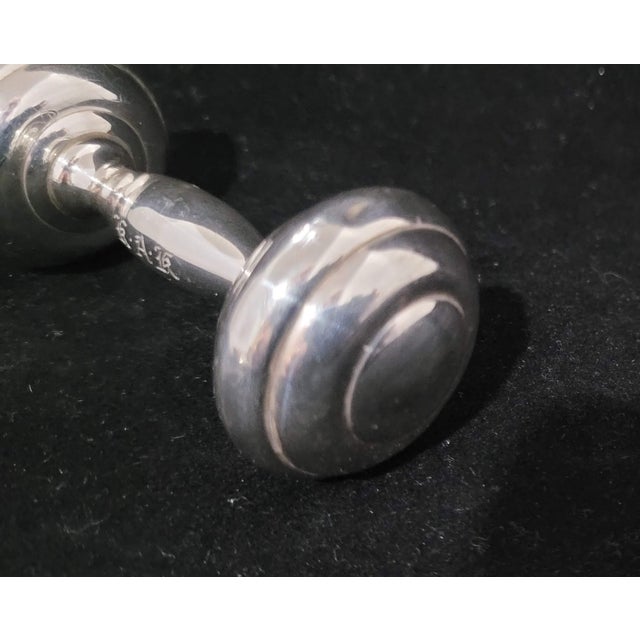 About the Piece: Elevate a silver collection or nursery display with this iconic sterling silver dumbbell baby rattle by...