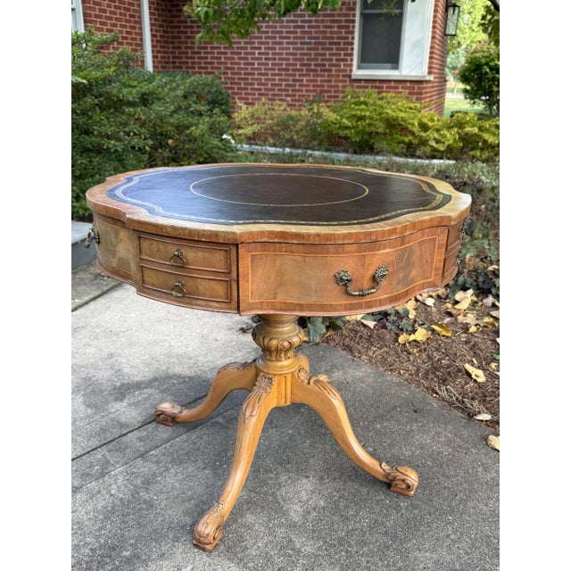 This Regency style solid wood drum table features a unique-shaped, gold-embossed and tooled brown leather inlaid top with...