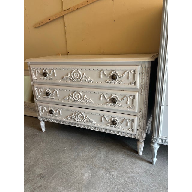 A striking French neoclassical dresser featuring intricate hand-carved garland, floral, and medallion motifs throughout....