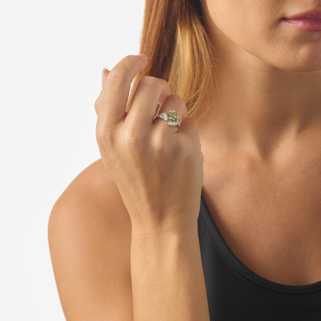 This striking mid-century engagement ring centers on a substantial 6.29 carat round brilliant cut diamond certified by GIA...