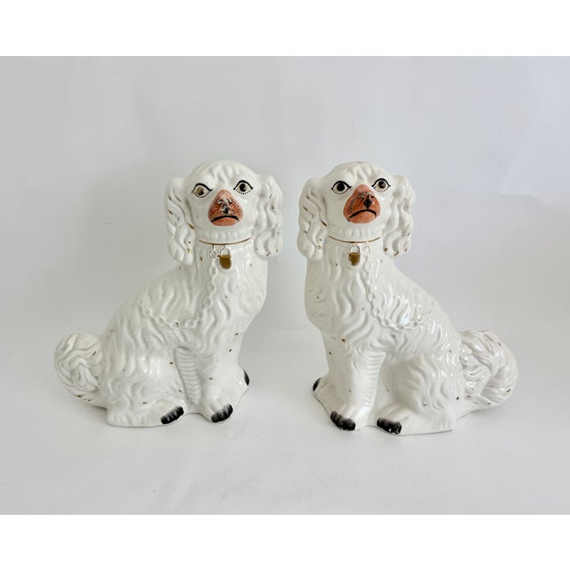 This pair of English matched left-and right-facing pair of seated Staffordshire ceramic Spaniel figurines feature a glossy...