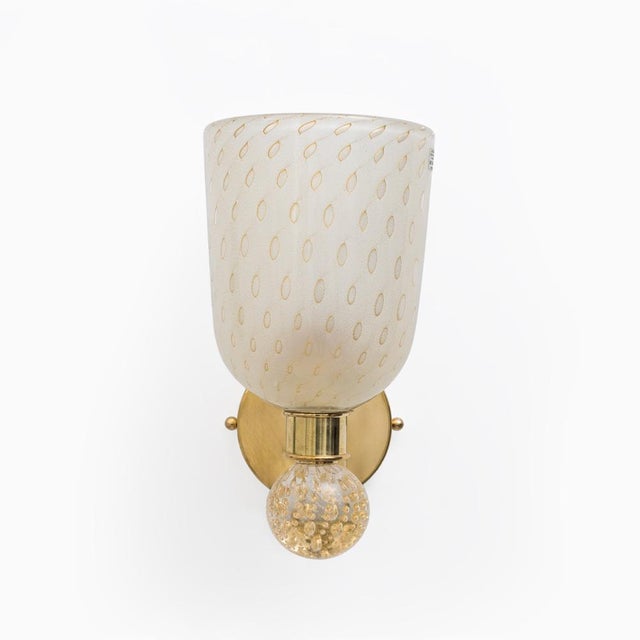 An elegant pair of italian wall lamps with hand-blown murano "pulegoso" glass shades. The slightly tapered white glass...