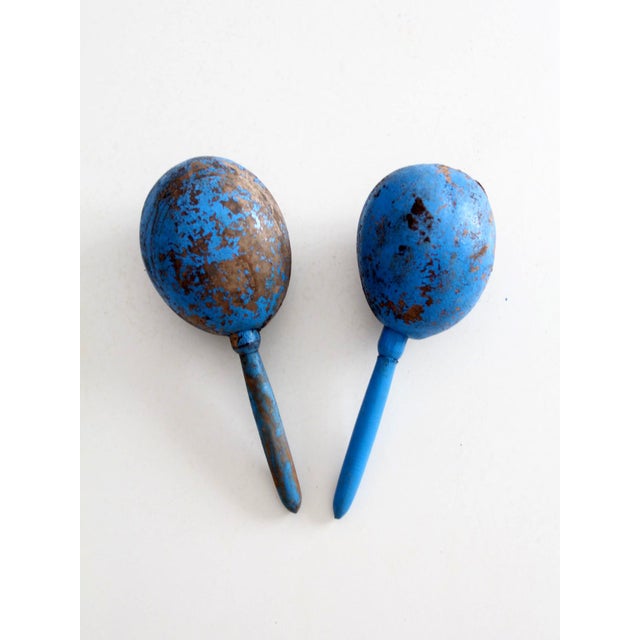 A vintage Mexican wood maracas, hand-painted in a saturated cobalt blue and decorated with whimsical folkloric figures in...