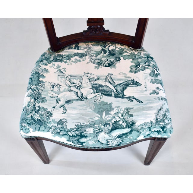 An antique Victorian Regency-style side desk chair of carved mahogany featuring Neoclassical design elements in the reeded...