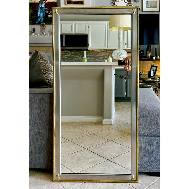 A French Directoire style wall or leaner mirror with neoclassical mixed-metal composition. The outer frame is constructed...