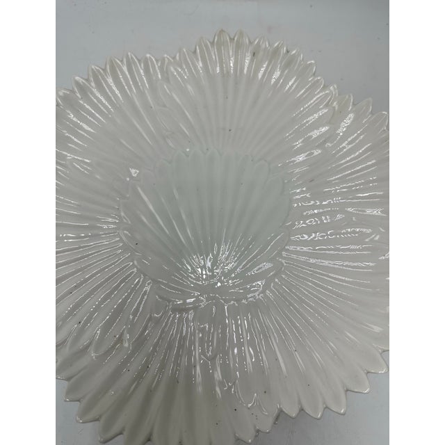 This is a set of white ceramic shell-form plates. The plates are molded in a scallop shell design with deeply radiating...